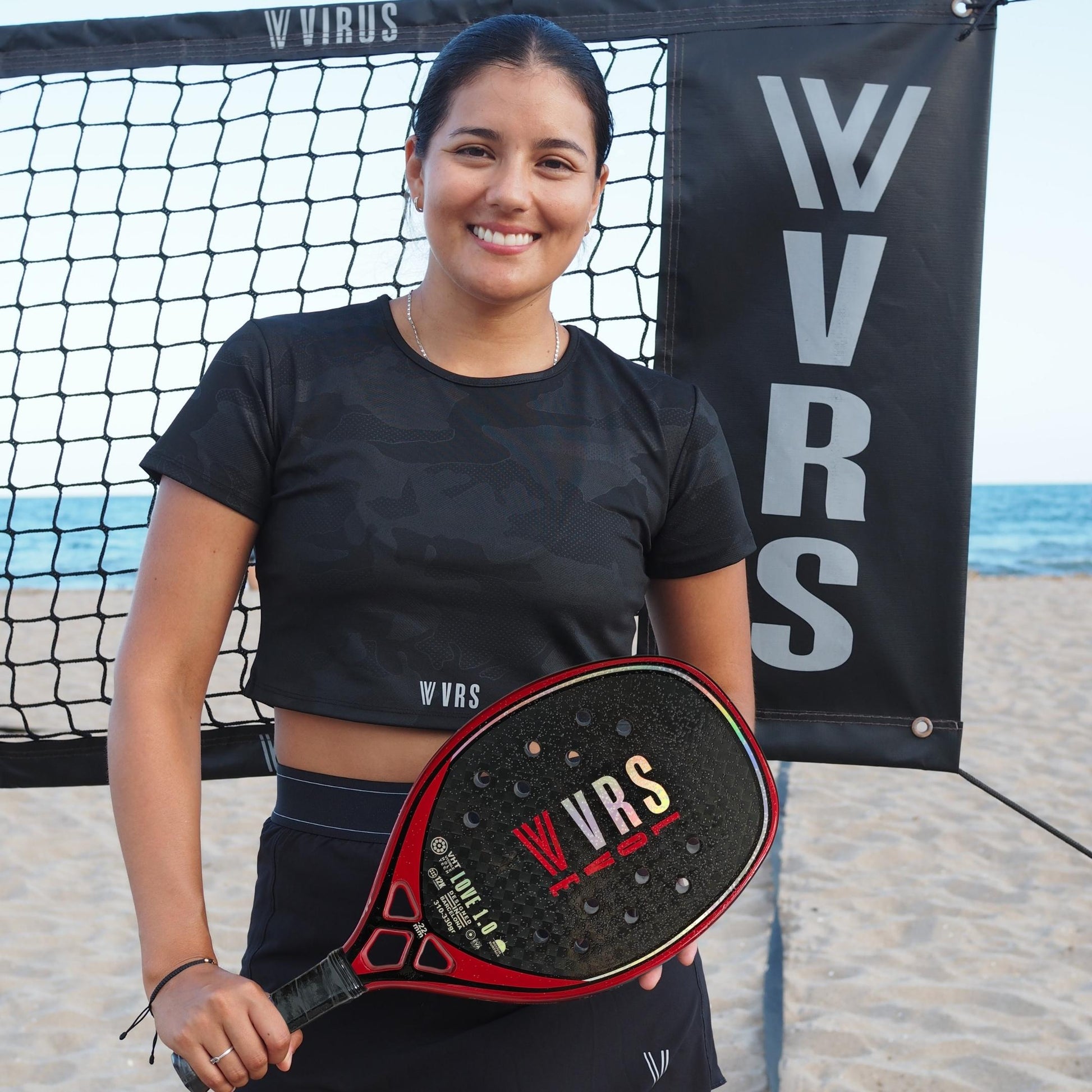Jugadora con la raqueta VIRUS LOVE 1.0 en pista de beach tennis
